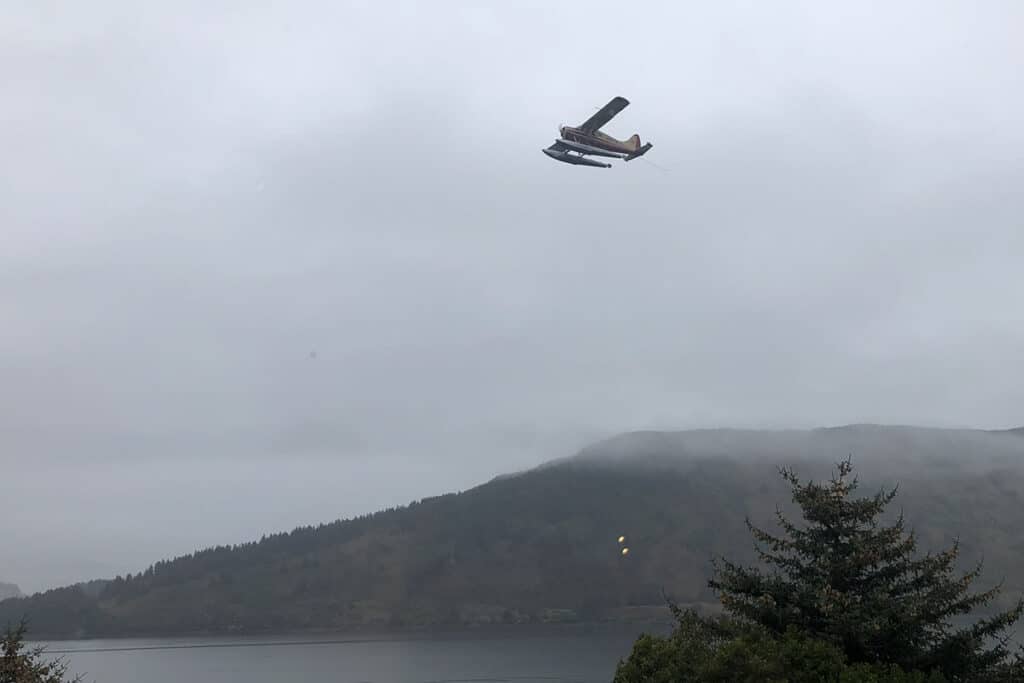 seaplane flies over foggy inlet