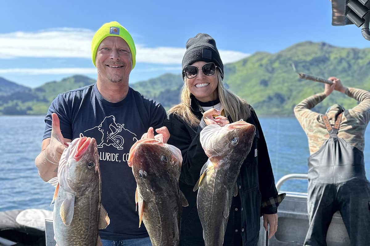 what is he chopping in the background? 2 people and their fish in focus