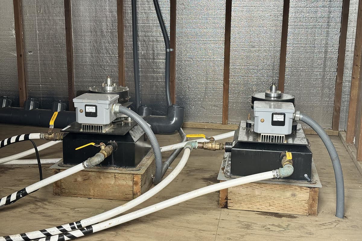 Two industrial pumps with hoses installed on wooden platforms in a construction site.